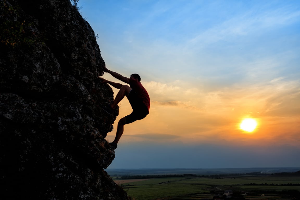 Young man climbing the mountain ridge